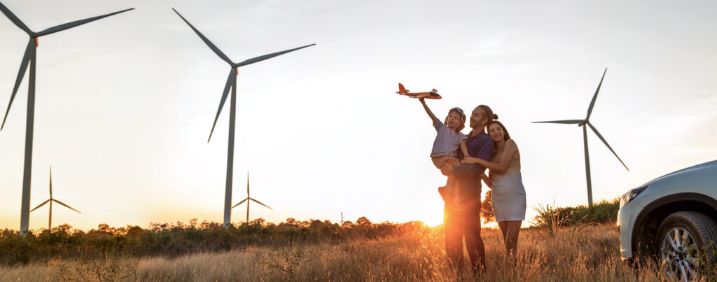 Family with son walking on field on wind farm. Happy Family and son playing at the Wind turbines generating electricity. Family time together.